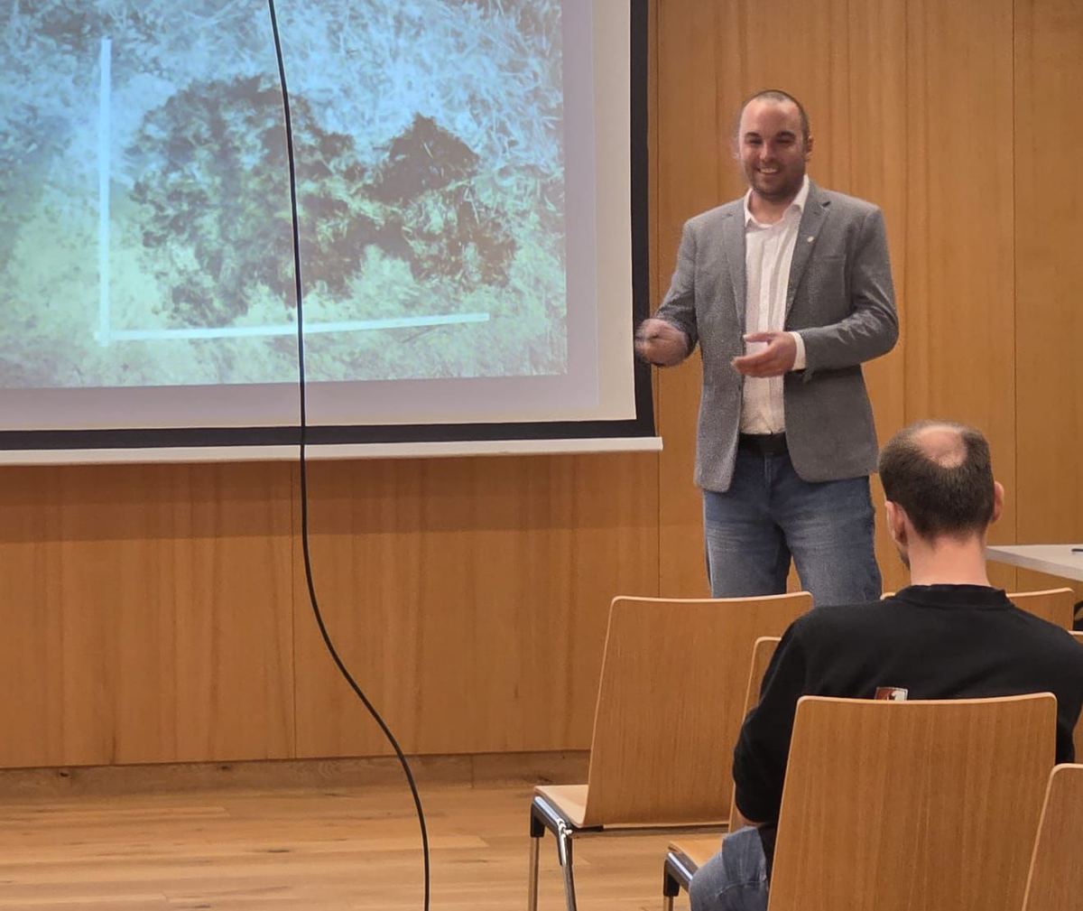 Robert Steiner bei einem Fachvortrag vor Publikum, im Hintergrund eine projizierte Brandortaufnahme